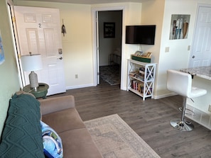 A living room with a brown sofa, a white chair, a TV, and a bookshelf.