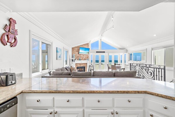 Una cocina amplia con una isla grande, muebles blancos y vista a la playa.