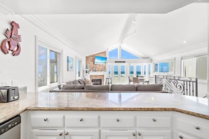 A spacious kitchen with a large island, white cabinetry, and a view of the beach.