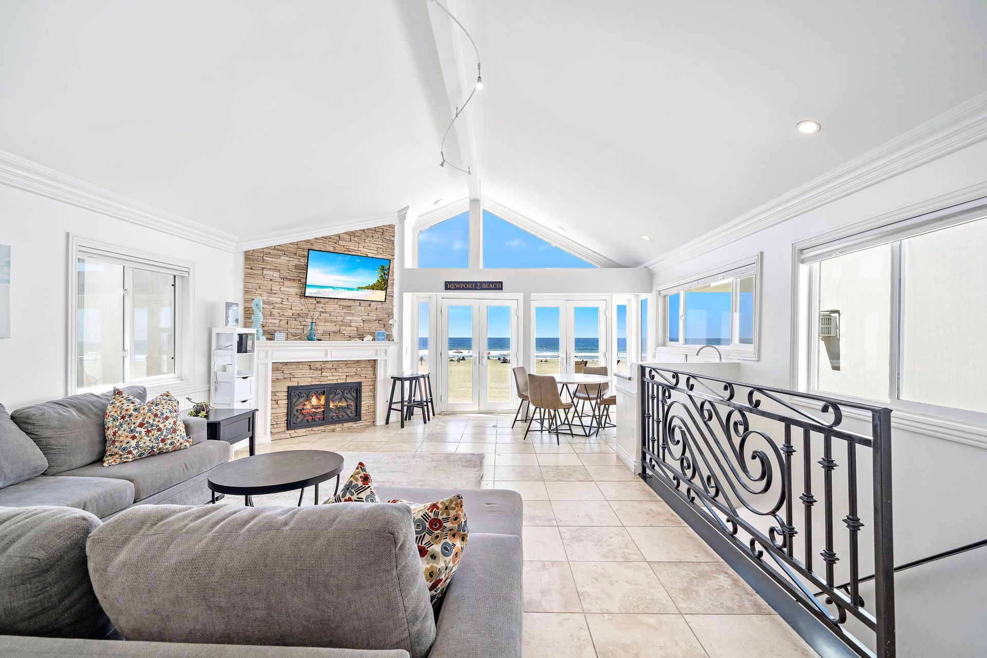 A spacious living area with a fireplace, a large sofa, and a view of the beach.