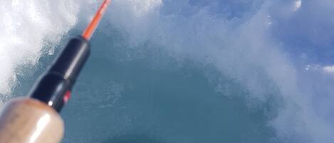 A close-up of a fishing rod with a hook in a hole in the ice.