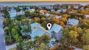 An aerial view of a coastal residential area with houses, a swimming pool, and a view of the ocean.