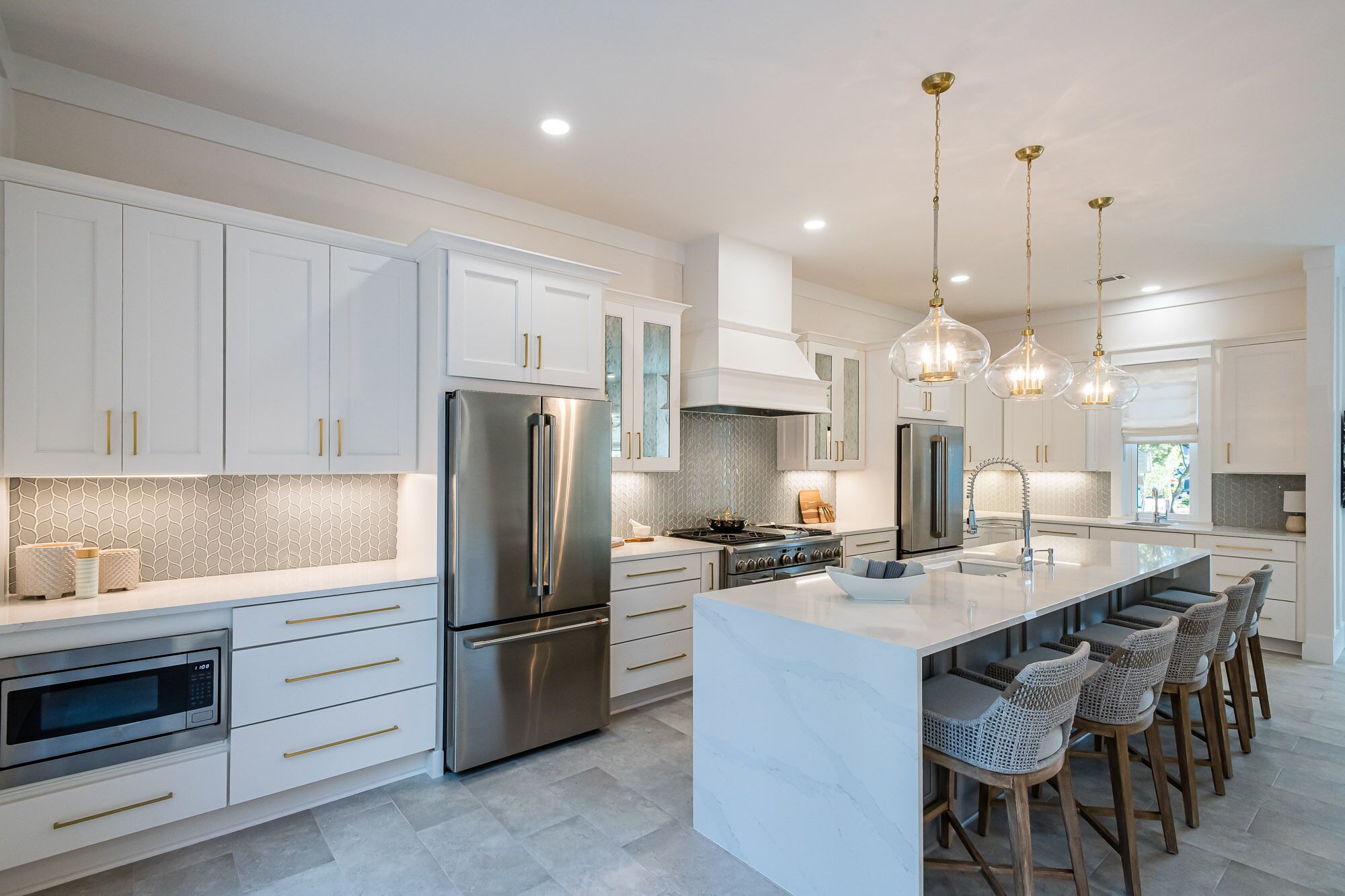 A modern kitchen with white cabinets, stainless steel appliances, and a central island with bar stools.