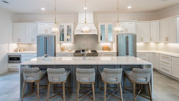 A modern kitchen with white cabinets, stainless steel appliances, and a central island with bar stools.