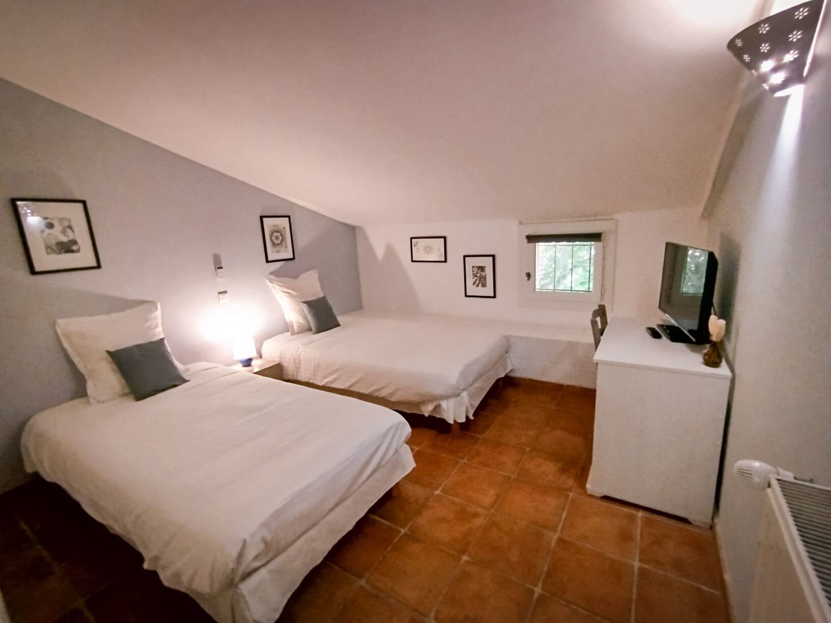 Een kleine, gezellige kamer met twee bedden, een bureau en een televisie.