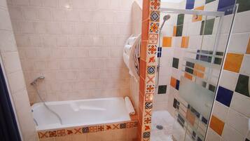 Une salle de bain équipée d’une baignoire, d’une douche et d’un espace de douche séparé par des parois en verre.