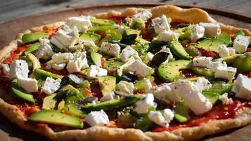 Une pizza garnie, servie sur une planche en bois.