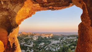 A view through a natural rock arch overlooking a historic town with buildings and greenery. - Le Mas De Gleyzes (Ledenon)