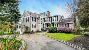 A large, two-story house with a front porch, a driveway, and a well-maintained lawn. - 22 minutes to Foxboro - FIFA GAMES 20 MINUTE AWAY - SLEEPS 10, FITNESS AND SPA (Milton)