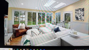 A spacious room with a large window, a sofa, a coffee table, and a painting on the wall. - 22 minutes to Foxboro - FIFA GAMES 20 MINUTE AWAY - SLEEPS 10, FITNESS AND SPA (Milton)