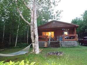 Eine Holzhütte mit Veranda, umgeben von Bäumen und einer Hängematte.