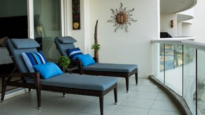 Un balcón con dos sillones de descanso, un adorno en la pared y vistas a la piscina.