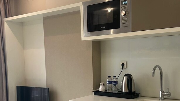 Una kitchenette compacta con microondas, pileta y una pequeña mesada.