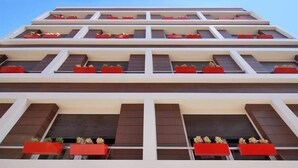 Un edificio de varios pisos con balcones, cada uno adornado con toldos rojos y macetas con plantas.
