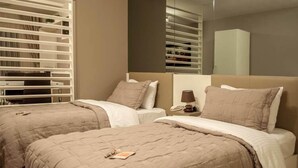 Una habitación de hotel con dos camas, una mesita de noche con lámpara y un espejo grande.