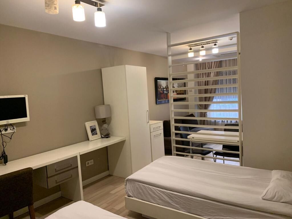 A bedroom with a bed, a desk, a wardrobe, and a built-in shelving unit.