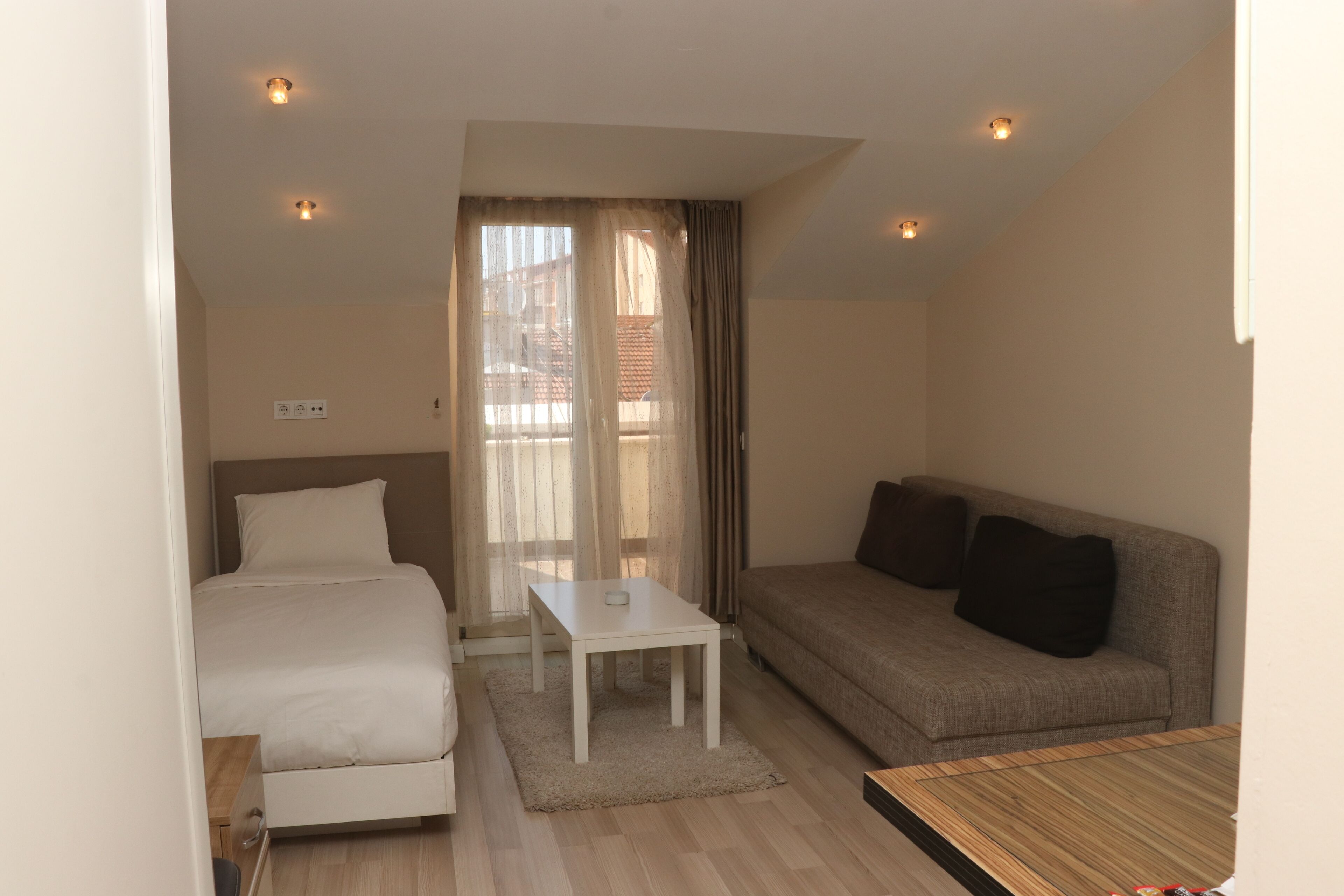 Una habitació d'hotel amb un llit, un sofà, una taula petita i una finestra amb cortines.