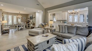 A spacious living room with a large sofa, a coffee table, and a dining area with a table and chairs.