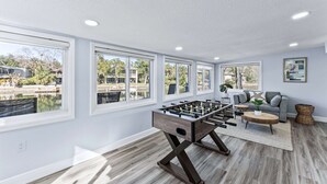 A spacious room with a foosball table, large windows, and a view of a body of water. - Our piece of paradise! (Weeki Wachee)