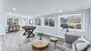 A spacious living room with a foosball table, a sofa, and a view of a body of water through large windows. - Our piece of paradise! (Weeki Wachee)