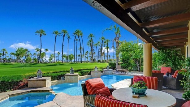 A pool area with outdoor seating and a view of a golf course.