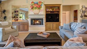 A living room with a fireplace, a sofa, a coffee table, and a bookshelf.