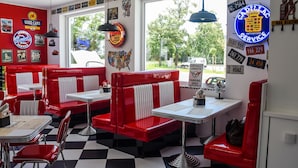 A diner with red booths, white countertops, and vintage license plates on the walls. - Motel Eldorado (Mikulov)
