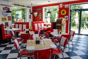 A diner with red booths and tables, vintage Chevrolet signs, and a jukebox. - Motel Eldorado (Mikulov)