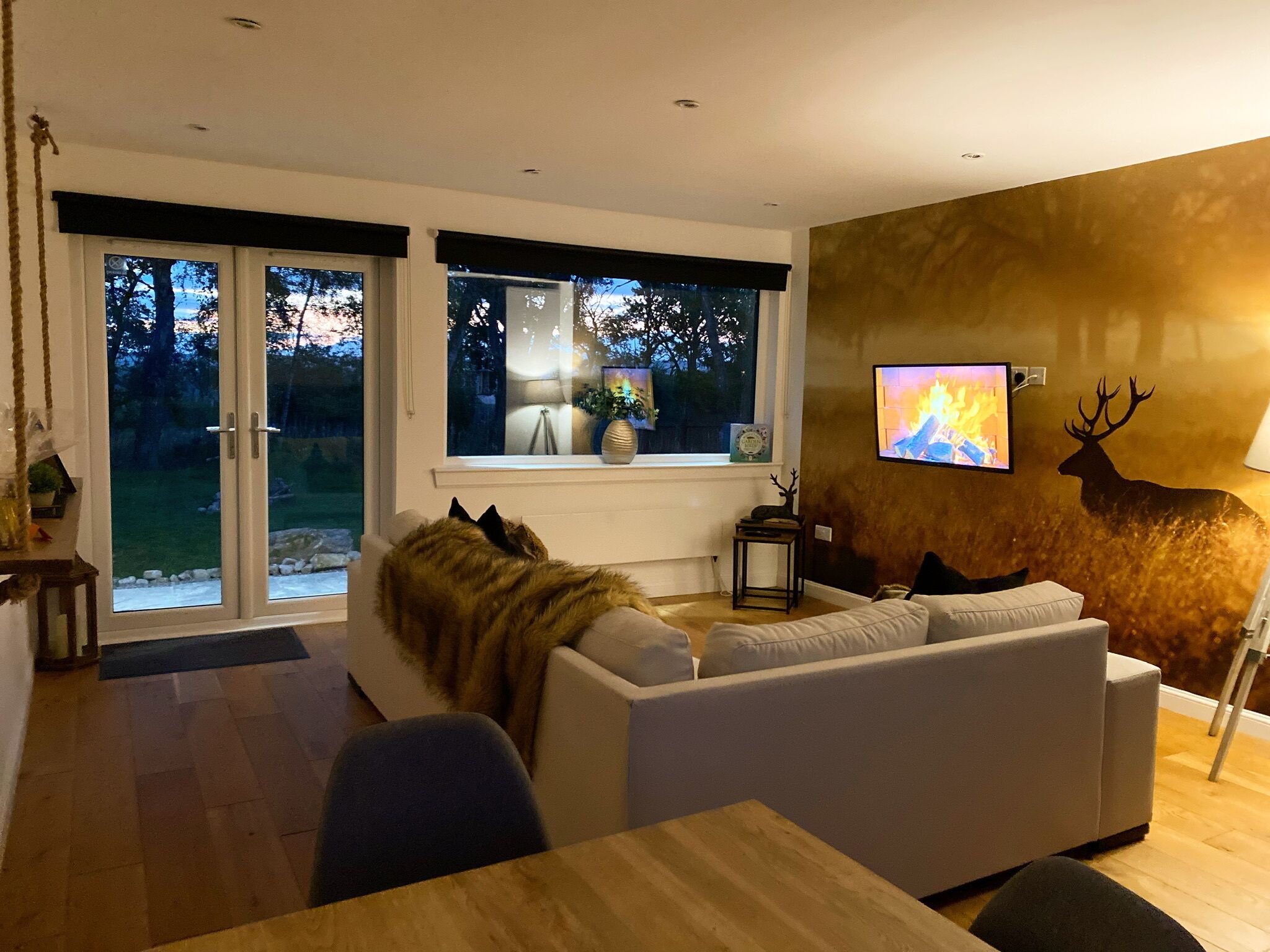 A modern living room with a sofa, a television, and a deer wall decal.