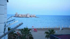 A beach with umbrellas and a castle-like structure in the background. - Hotel Angel Beach (Erdemli)