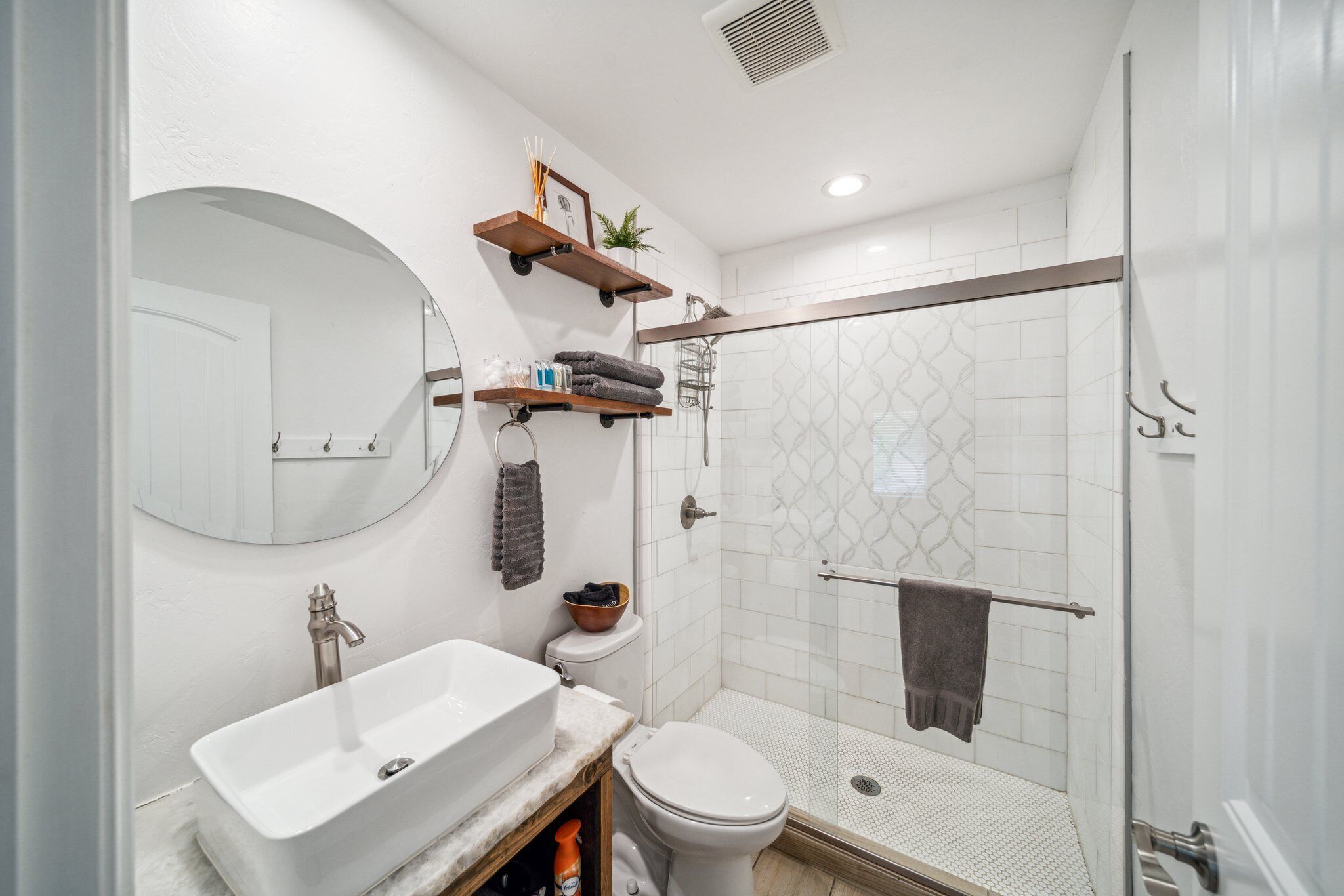 Un baño moderno con lavamanos independiente, inodoro y ducha a ras de suelo.