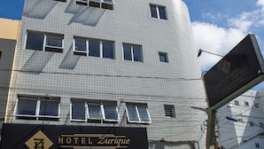 Ett hotell med flera våningar, en fasad med ett rutmönster, en framträdande entré och en skylt som annonserar hotellet.