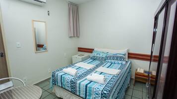 Een slaapkamer met een bed, nachtkastje, stoel, spiegel en een airconditioning.