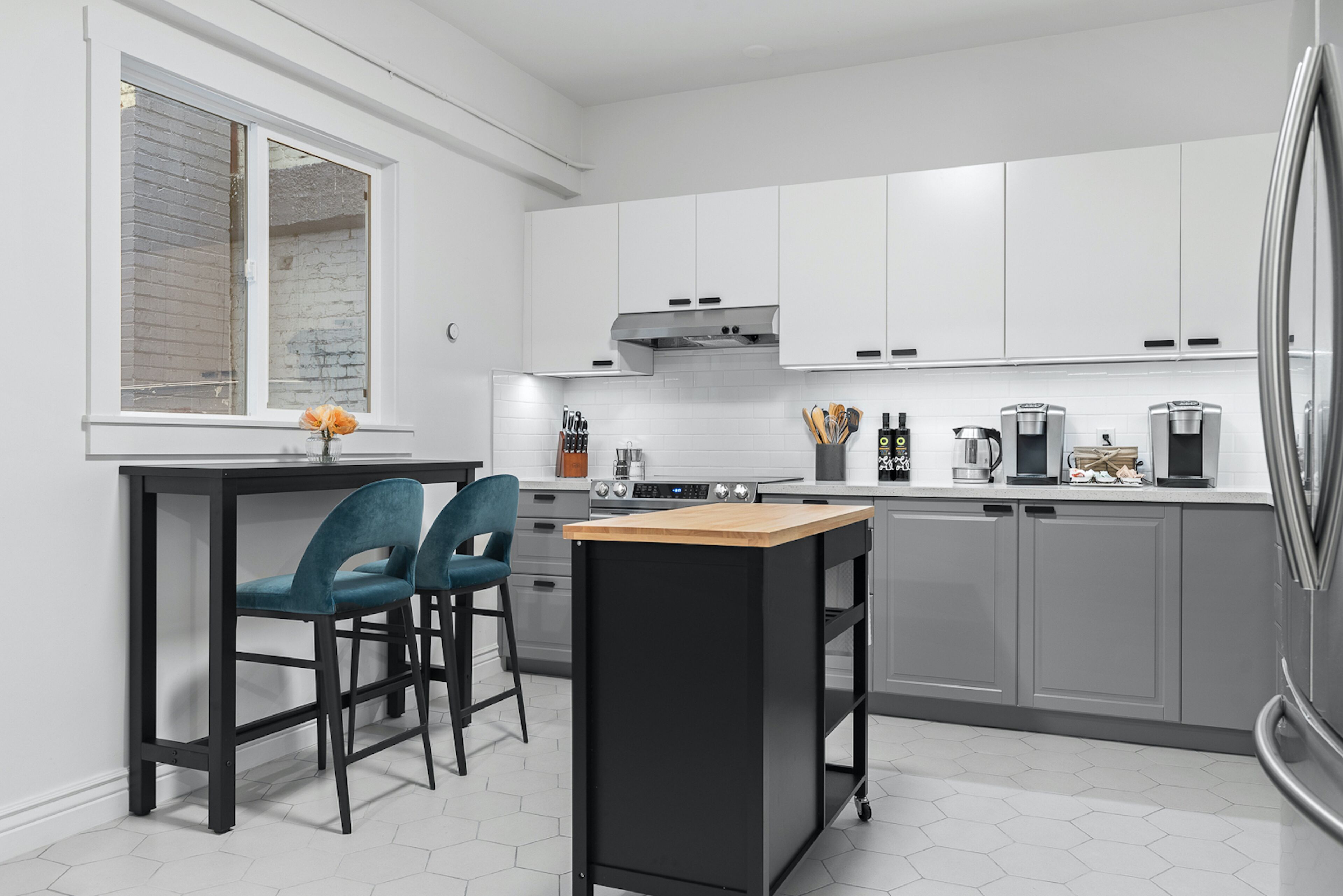 A modern kitchen with white cabinets, a black countertop, and a window with a view of the outside.