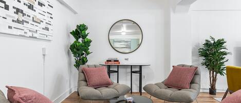 Una sala de estar moderna con dos sofás grises, una mesa redonda y una mesita con un espejo y libros.