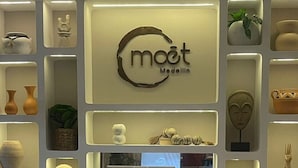 A wall with a central logo and various cultural artifacts displayed in recessed shelves. - Moet Medellin Hotel (Medellín)