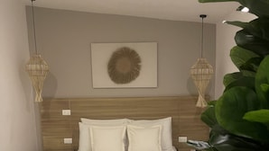 A neatly arranged bedroom with a wooden headboard, a bed with white linens, two hanging lamps, and a wall-mounted decorative plate. - Moet Medellin Hotel (Medellín)