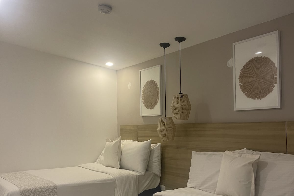 Ein Hotelzimmer mit zwei Betten, einem Holzkopfteil und zwei an der Wand befestigten Kunstwerken.