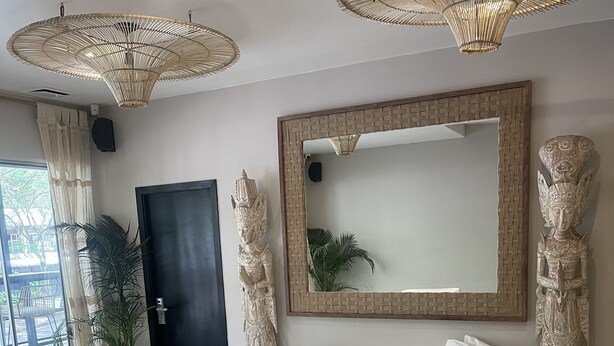 A modern living room with a sofa, a coffee table, and two chairs. There is a large mirror on the wall and a door with a decorative handle. - Moet Medellin Hotel (Medellín)
