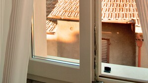 A window with curtains, revealing a view of a building with a tiled roof and a chimney. - Hotel Boutique Castiglione del Lago (Castiglione del Lago)