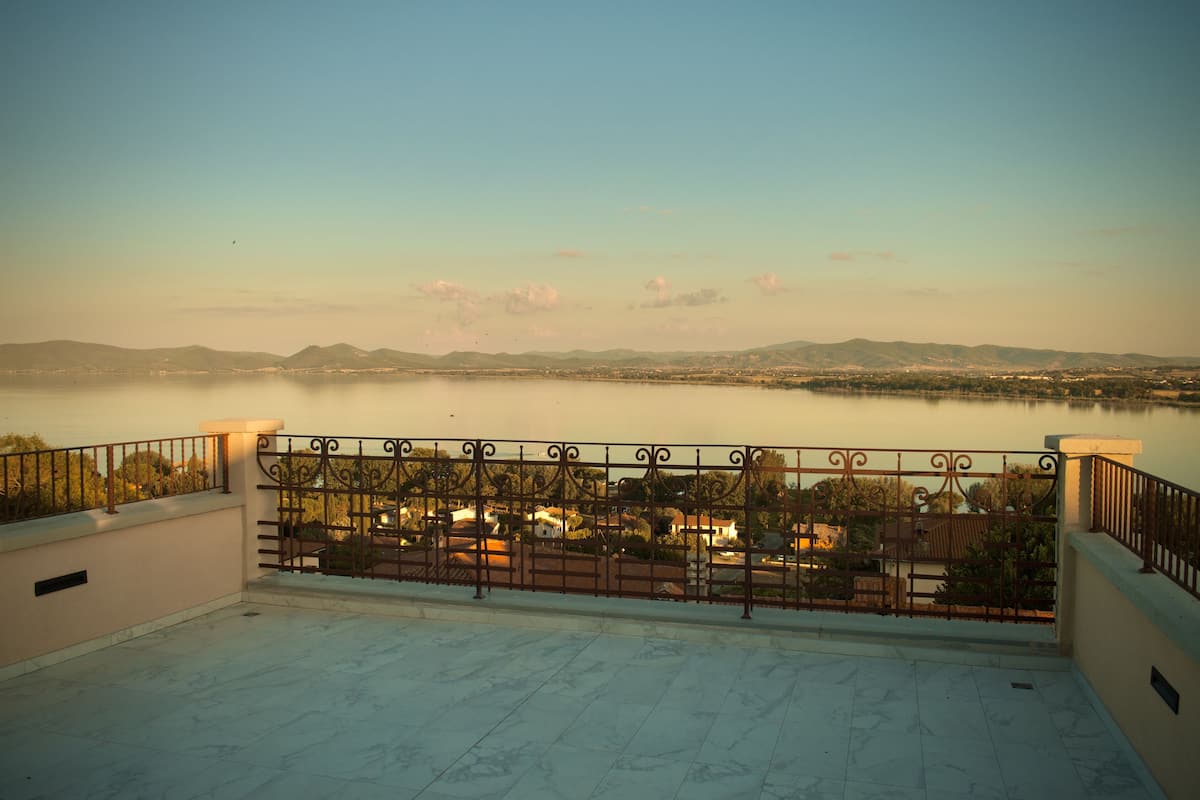 A terrace with a view of a lake and distant mountains.