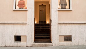 A building entrance with a staircase leading to a door marked with a logo. - Hotel Boutique Castiglione del Lago (Castiglione del Lago)