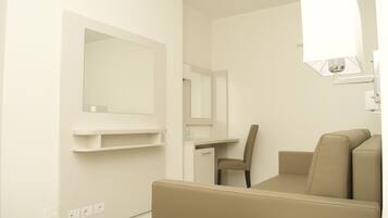 Una habitación de hotel minimalista con sofá, escritorio y silla.