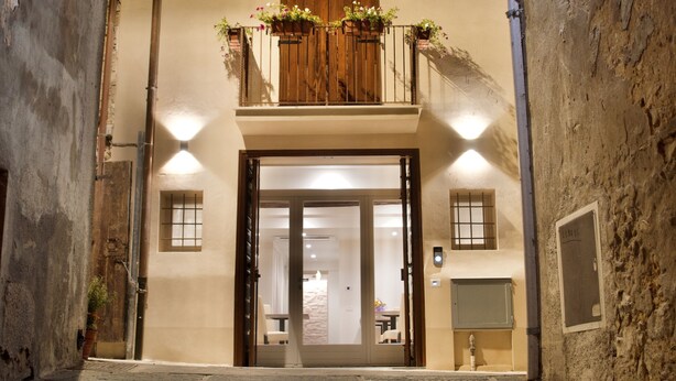 An arched entrance with a wooden balcony, a tiled floor, and a door leading inside. - Hotel Boutique Castiglione del Lago (Castiglione del Lago)