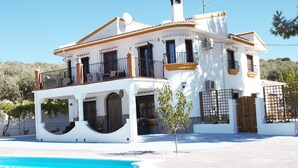 A two-story house with a swimming pool, balconies, and a gate. - Villa with private pool,  Mountain views and easy access to visit Andalucia  (Villanueva del Trabuco)