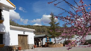 A white building with a stone base, a wooden bench, and a stone fountain in the courtyard. - Villa with private pool,  Mountain views and easy access to visit Andalucia  (Villanueva del Trabuco)