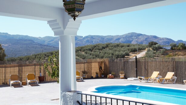 A pool area with a view of mountains, lounge chairs, and a decorative lantern. - Villa with private pool,  Mountain views and easy access to visit Andalucia  (Villanueva del Trabuco)