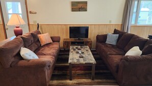 Ein Wohnzimmer mit zwei braunen Sofas, einem Holztisch, einem Fernseher und einer Lampe.