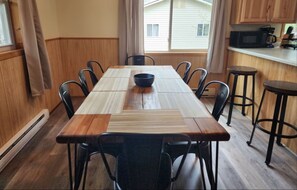 A dining area with a long wooden table, black chairs, and a black bowl on the table.