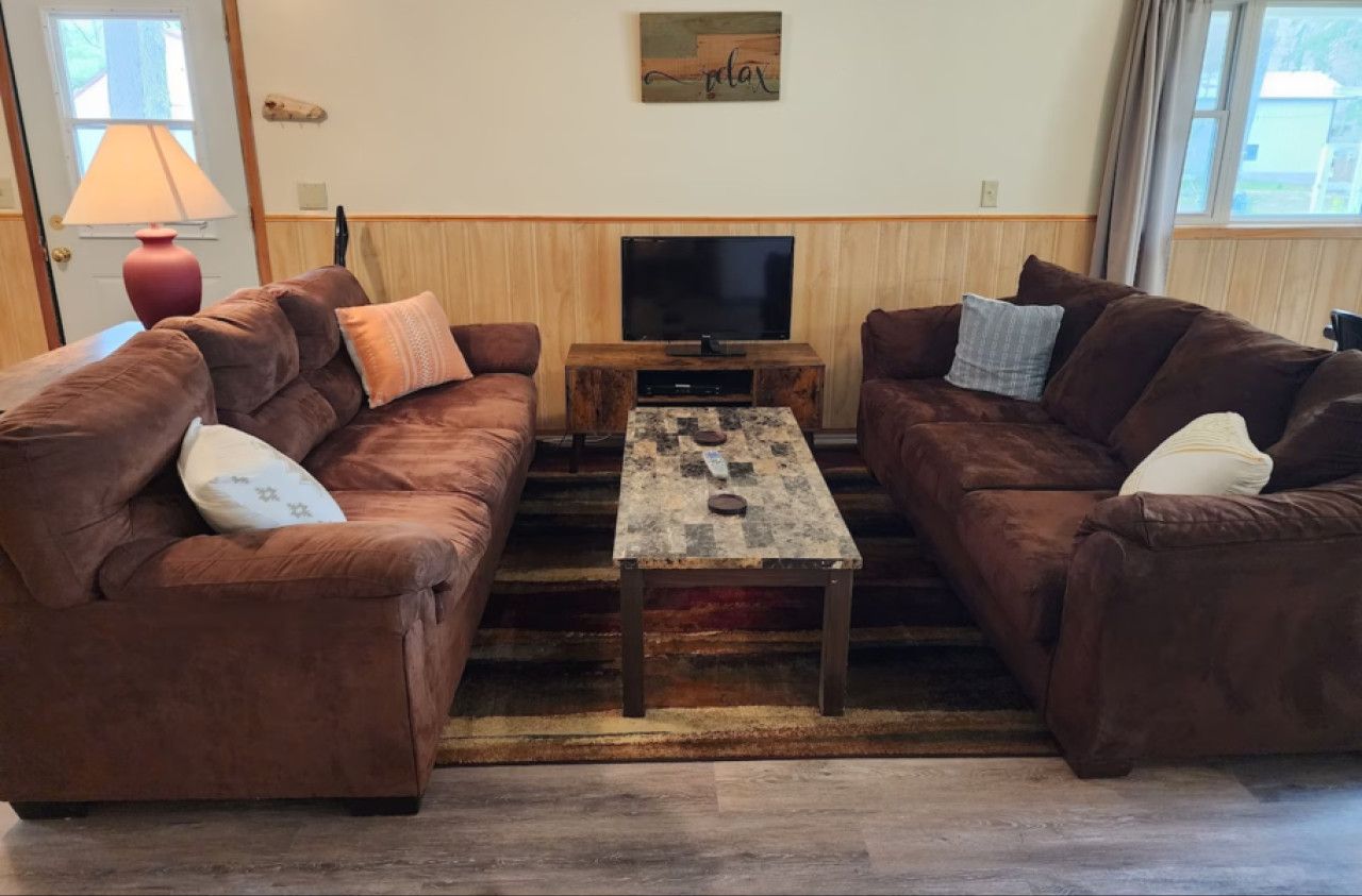 A living room with two brown sofas, a wooden coffee table, a TV, and a lamp.